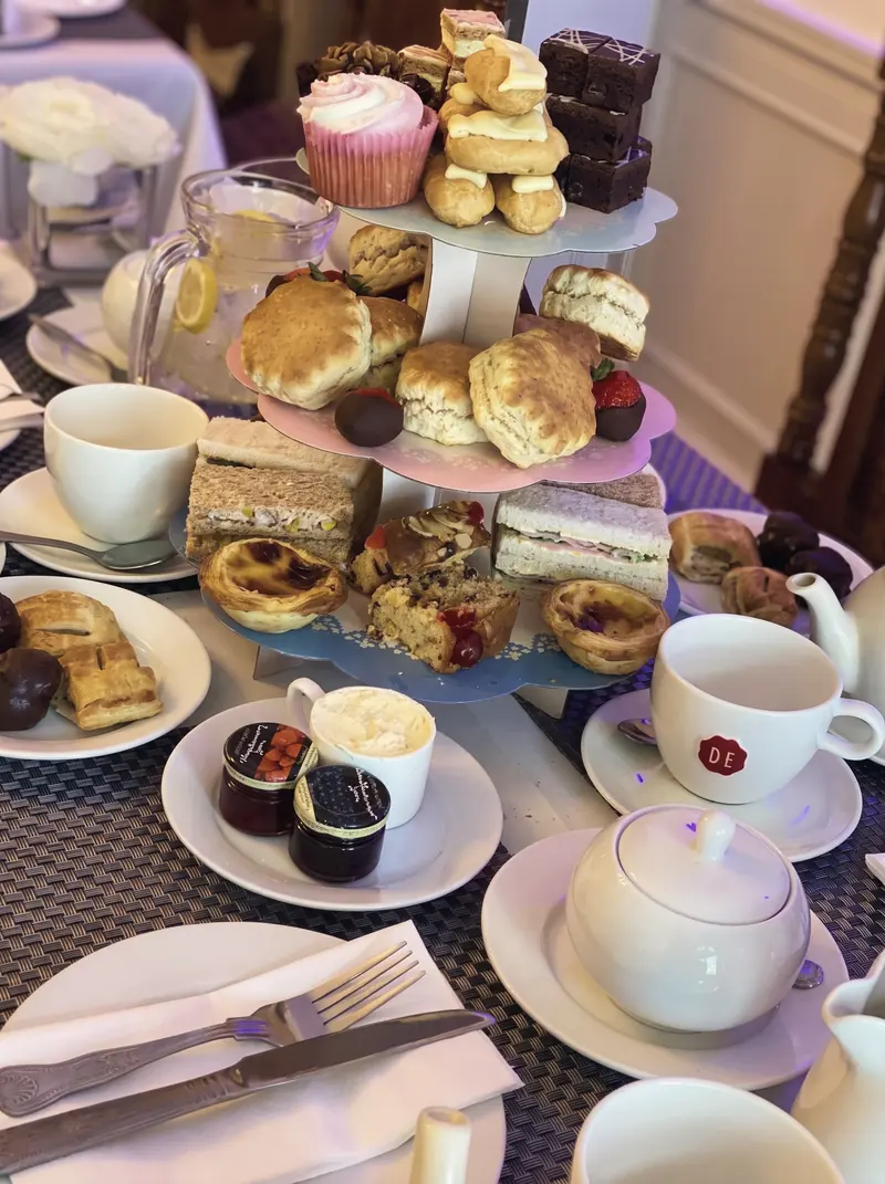 Afternoon tea on a tiered stand with scones, cakes, sandwiches and pots of tea