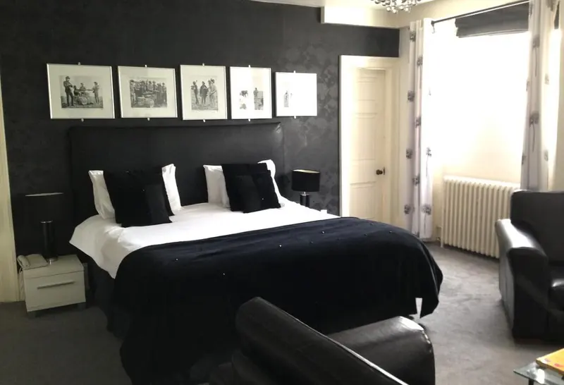 The Beatles Suite: a black and white bedroom with a double bed and framed photographs of the band on the wall