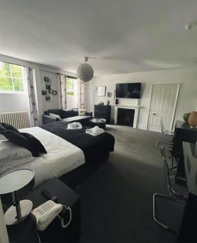 The Beatles Suite from the foot of the bed: a fireplace with a TV above it, framed photographs, and a tall window with a radiator beneath
