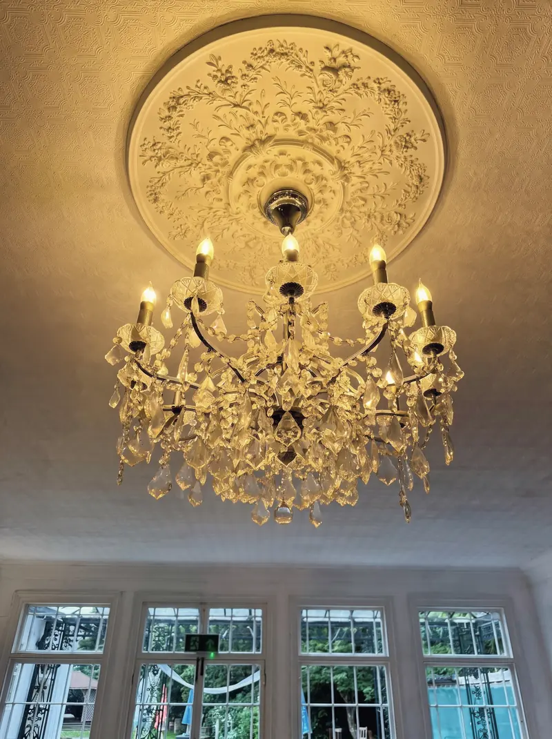 A crystal chandelier hanging from an ornate plaster ceiling rose