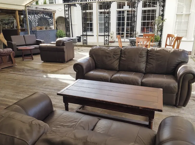 Leather sofas around a low wooden table on the covered terrace