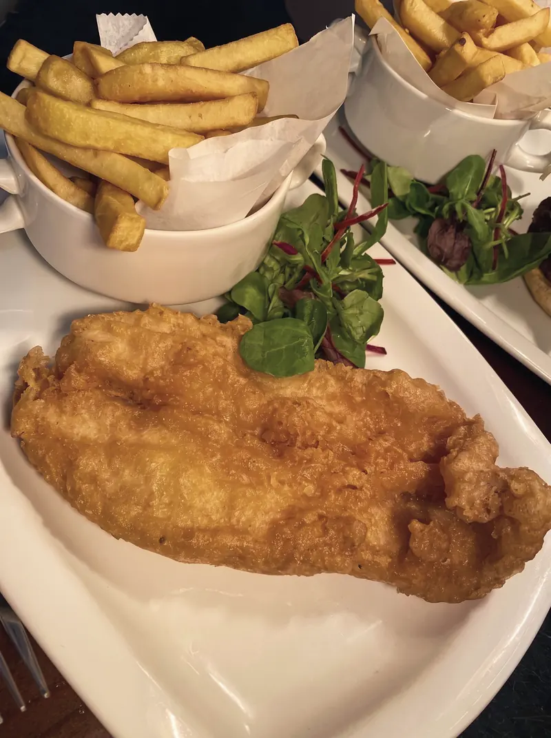 Battered fish with a bowl of chips