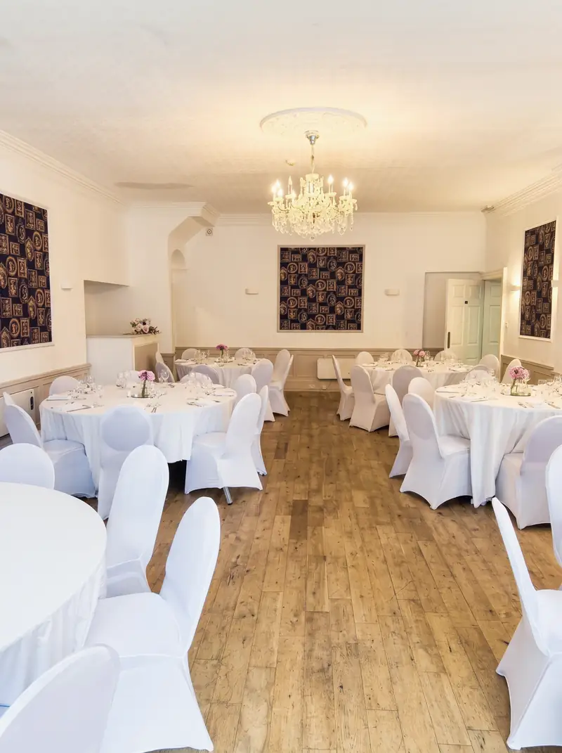Function room set in white for a reception, with a chandelier overhead