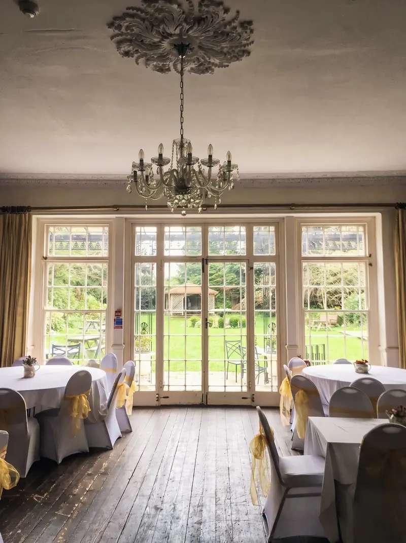 A function room with a chandelier and French doors opening onto the garden