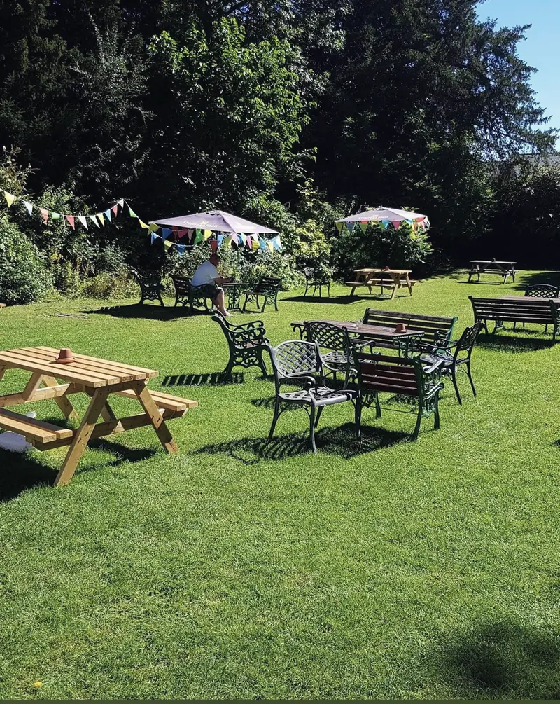 Picnic benches, garden tables and parasols on the lawn under strings of bunting