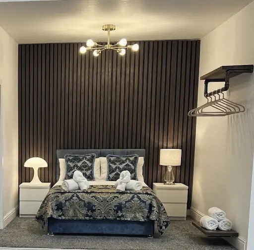 A model of the Small Double Room seen from the foot of the bed, with the slatted wall, brass ceiling light and hanging rail