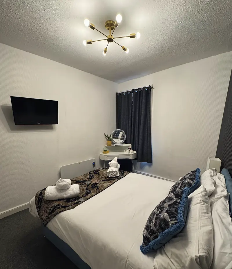 The Small Double Room from beside the bed, with the TV, the dressing table and the curtained window