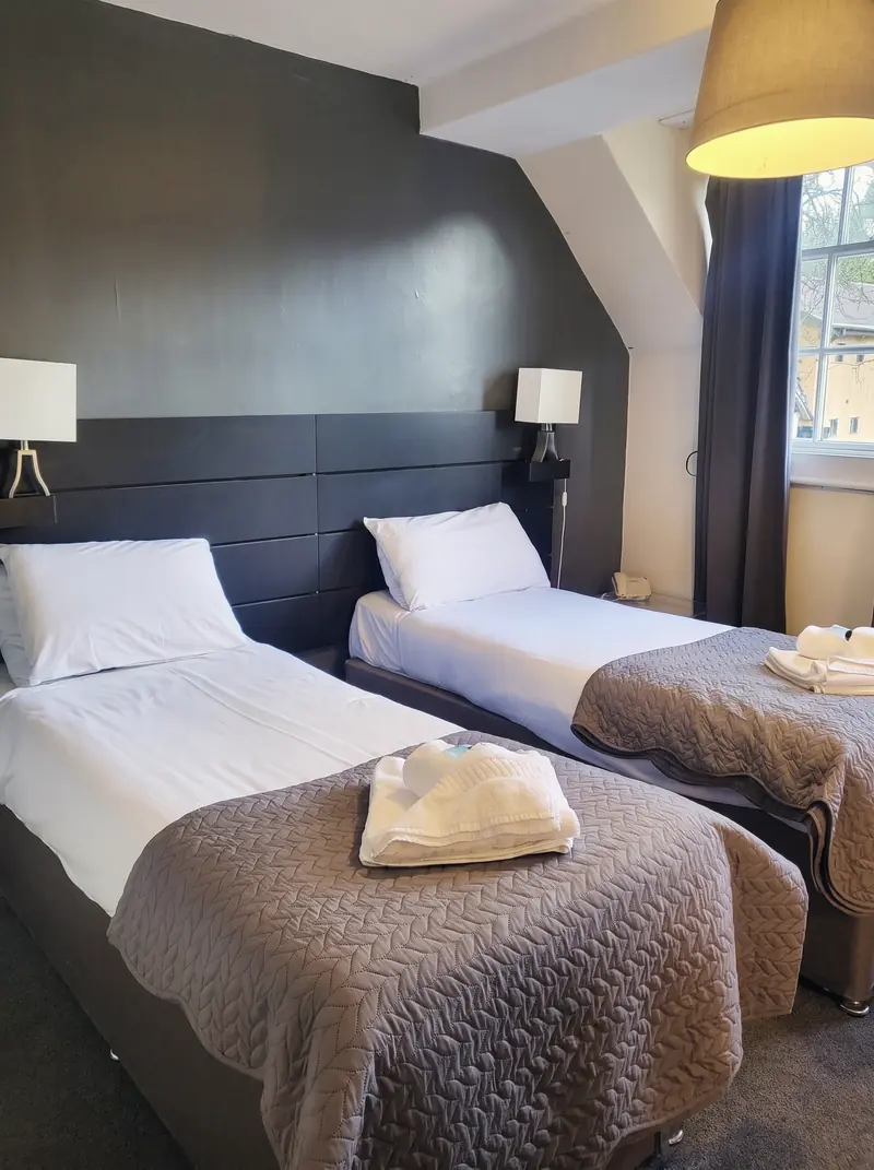 A twin room with two single beds and a dark panelled headboard