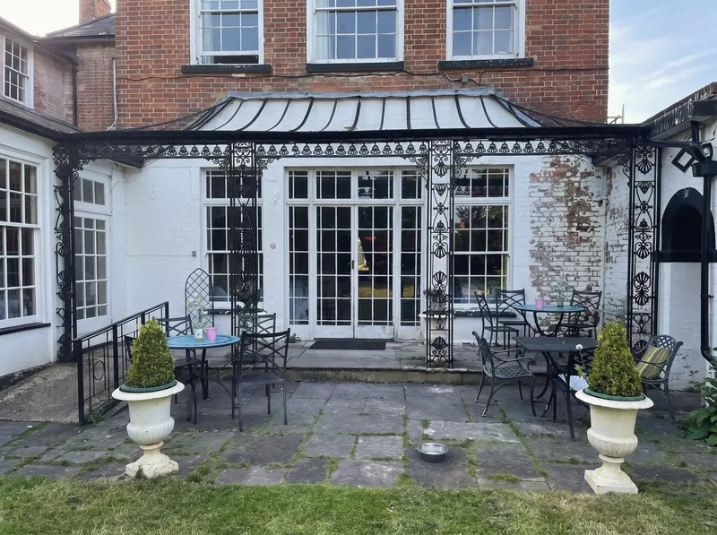 Iron and glass veranda with cafe tables outside the garden doors of the hotel